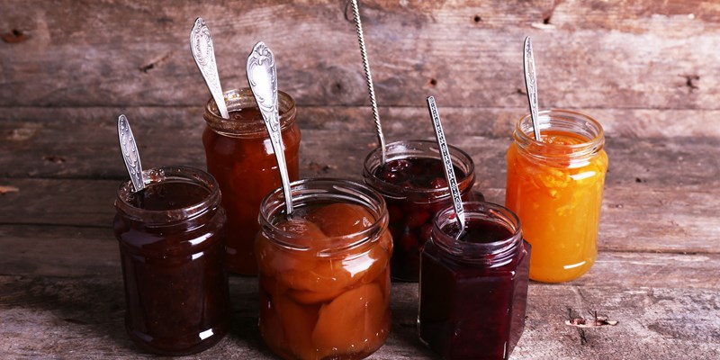 Jars of tasty jam on wooden background